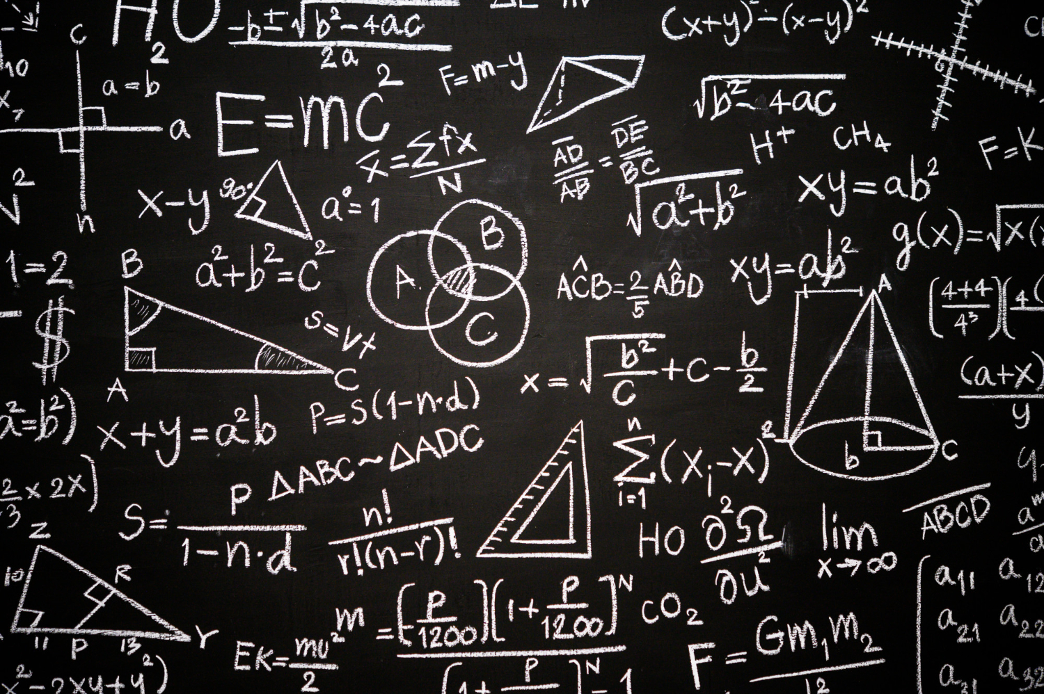 Czarna tablica szkolna zapisana białymi wzorami matematycznymi, równaniami i figurami geometrycznymi, jak gry matematyczne.